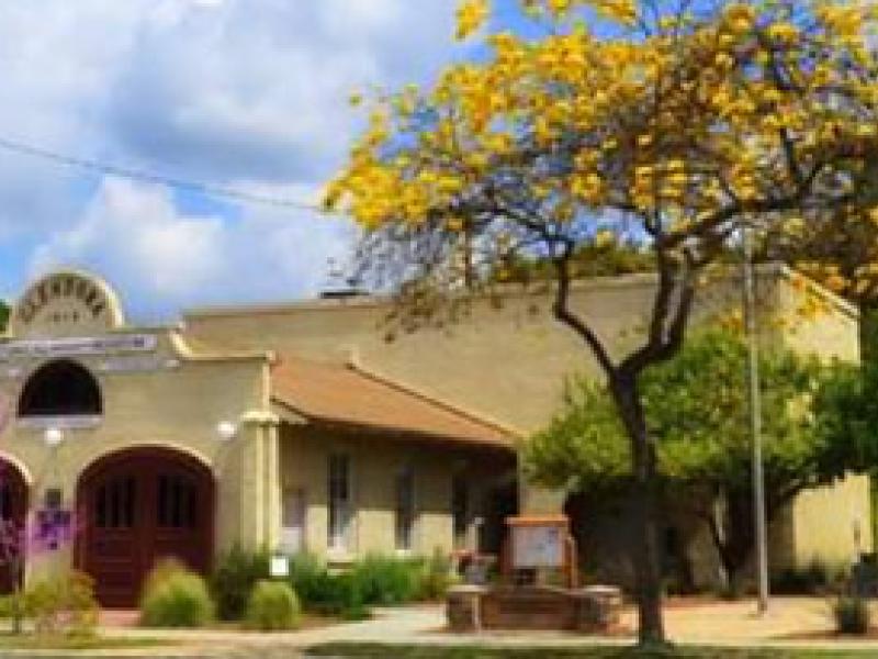 Image of historic fire house museum in downtown Glendora with yellow tree blooming.